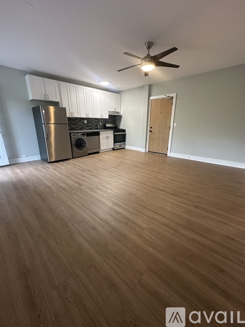 A room with wooden flooring and a stainless steel refrigerator.