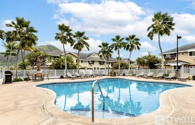 A pool surrounded by palm trees and lounge chairs.