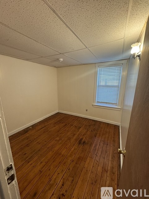 A room with wooden flooring and a window with blinds.
