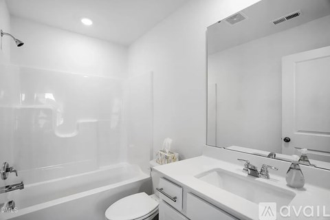 A white bathroom with a sink, mirror, and bathtub.