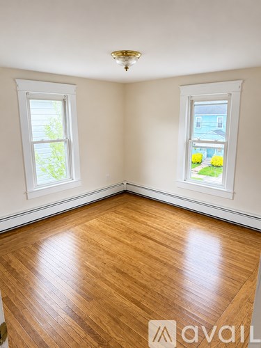 A room with wooden floors and two windows.