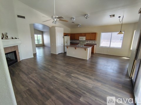 A spacious living room with wood flooring and a fireplace.