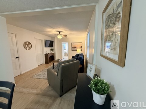 A living room with a couch, a chair, a plant, and a painting on the wall.
