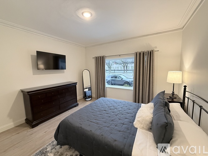 A bedroom with a bed, a dresser, and a window with a view of a snowy street.