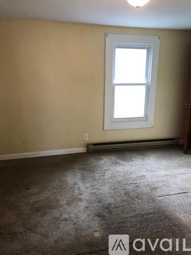 A room with a window and a carpeted floor.