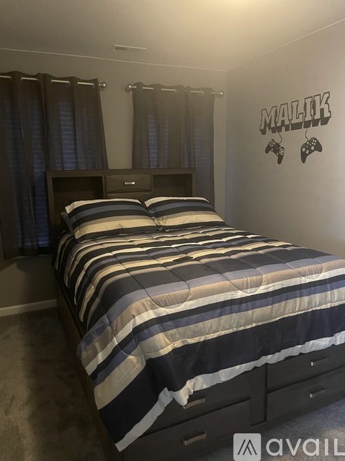 A bedroom with a bed, curtains, and a wall decal that says "MALIK".