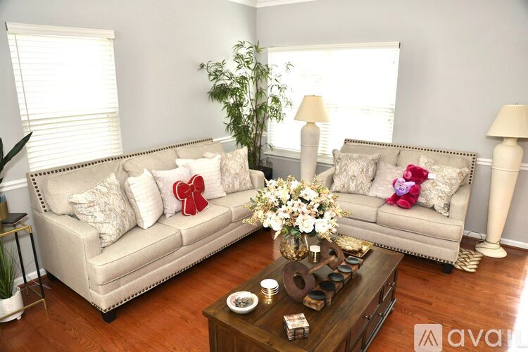 A living room with a white couch, a wooden coffee table, and a plant.