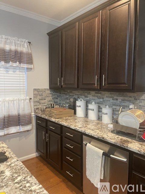 A kitchen with brown cabinets and a marble countertop.