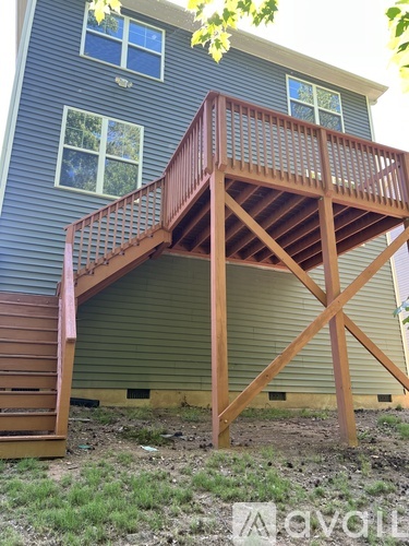 A wooden deck with a staircase leading to a house.