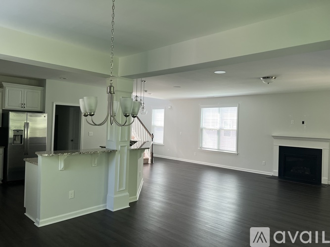 A spacious living room with a fireplace and a staircase leading to the upper floor.