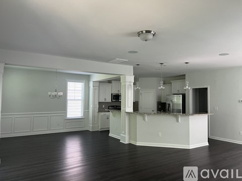 A spacious kitchen and living room with white cabinets and a wooden floor.