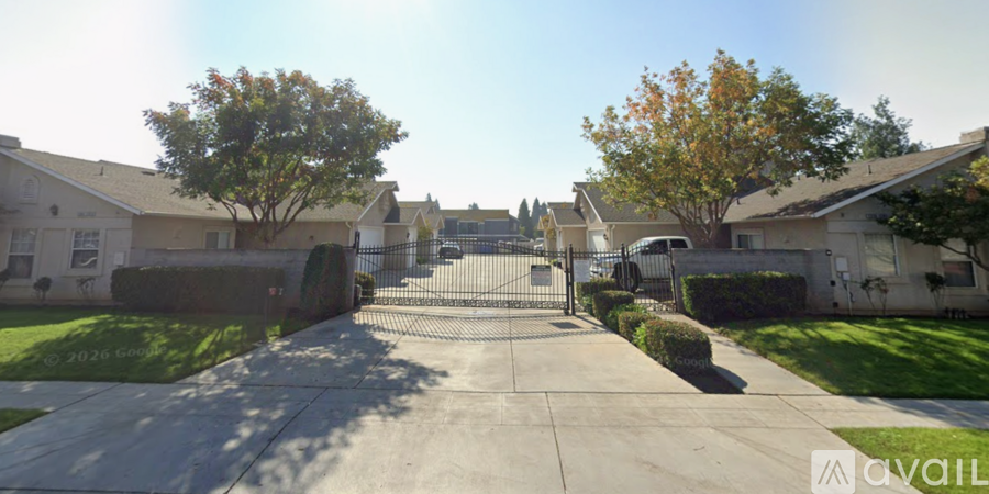 A gated entrance to a residential area with houses on either side.