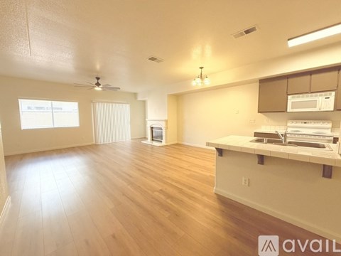 A spacious room with wooden floors and a kitchenette.