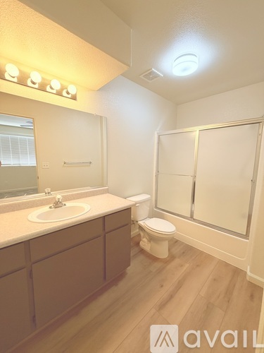 A bathroom with a toilet, sink, and mirror.