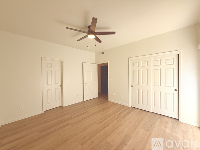 A room with a ceiling fan and three doors.