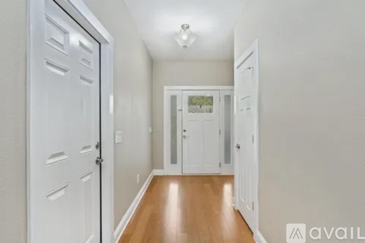 A hallway with white doors and a wooden floor.