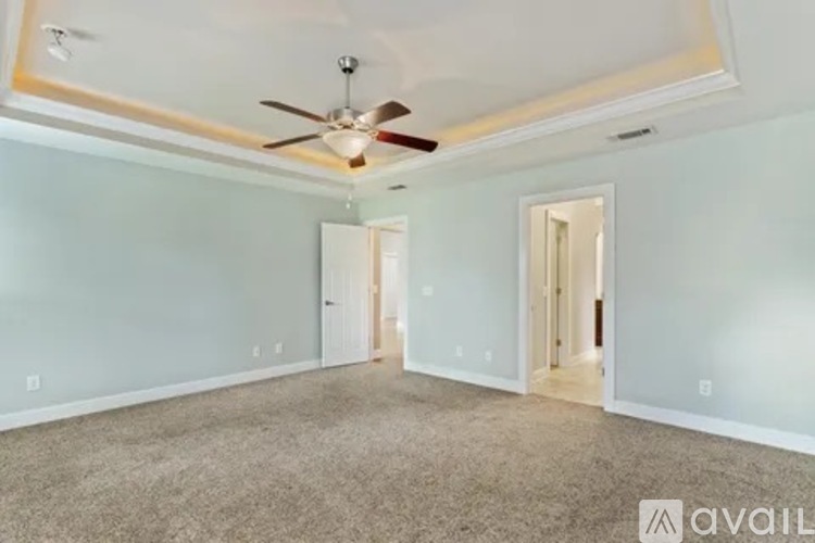 A spacious room with a ceiling fan and two doors.