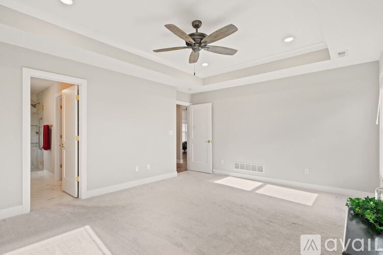 A spacious room with a ceiling fan and a carpeted floor.