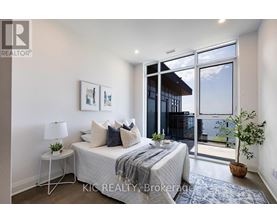 A bedroom with a bed, nightstand, and a window with a view of the outside.