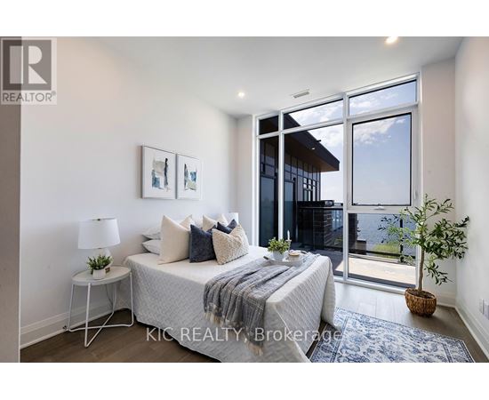 A bedroom with a bed, nightstand, and a window with a view of the outside.