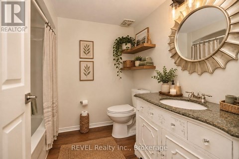 A bathroom with a toilet, sink, and mirror.