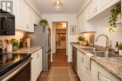 A kitchen with white cabinets and a black microwave.