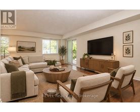 A living room with a white couch, a wooden coffee table, and a flat-screen TV mounted on the wall.