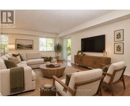 A living room with a white couch, a wooden coffee table, and a flat-screen TV mounted on the wall.