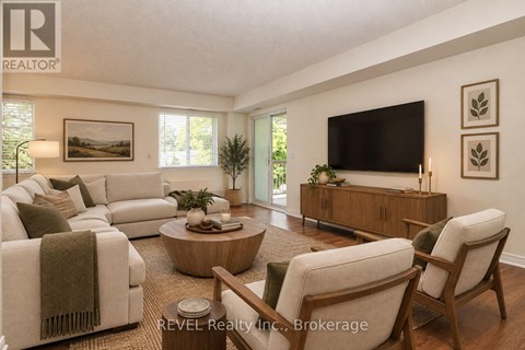 A living room with a white couch, a wooden coffee table, and a flat-screen TV mounted on the wall.