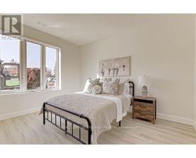 A bedroom with a large bed, a nightstand, and a painting on the wall.