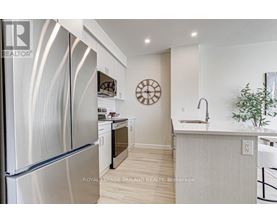 A modern kitchen with a stainless steel refrigerator and a wooden floor.