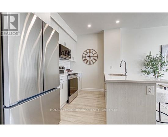 A modern kitchen with a stainless steel refrigerator and a wooden floor.
