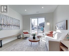 A living room with a white couch, a red pillow, and a large window.