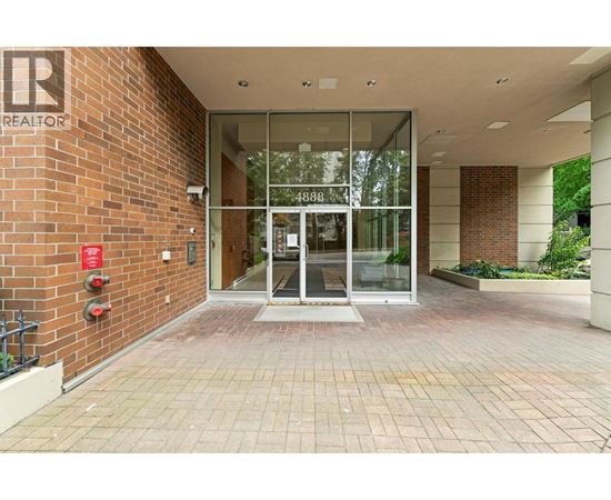 The image shows a glass door entrance to a building with a brick wall on one side and a fire extinguisher on the other.