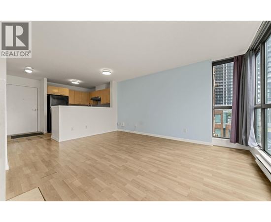 A spacious room with wooden flooring and a large window.