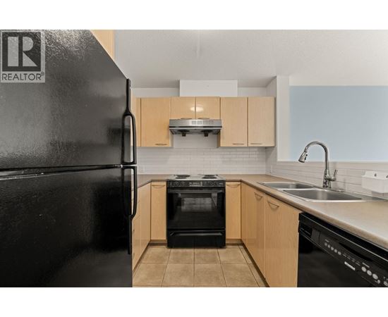 A black refrigerator with a logo on it in a kitchen.