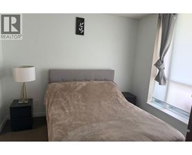 A bedroom with a bed, nightstand, and a table with a vase on it.