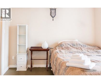 A bedroom with a bed, nightstand, and a table with a vase on it.