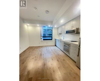 A well-lit kitchen with wooden flooring and modern appliances.
