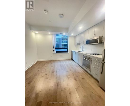 A well-lit kitchen with wooden flooring and modern appliances.