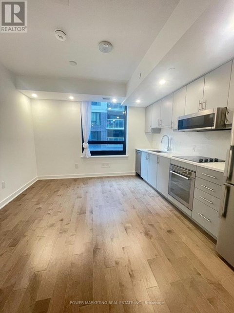A well-lit kitchen with wooden flooring and modern appliances.