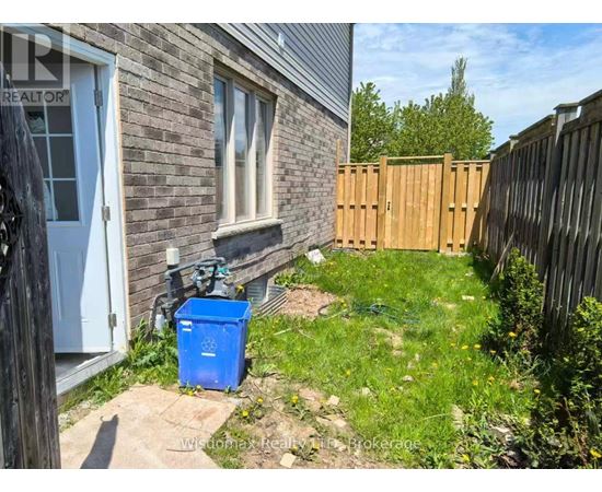 A blue recycling bin sits in front of a house.
