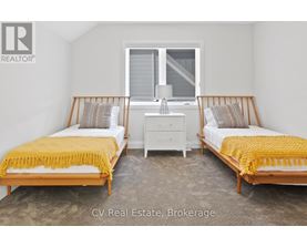 A bedroom with two beds and a nightstand.