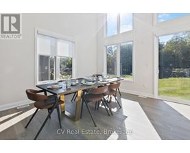 A dining room with a table set for six and a view of a lawn outside the window.