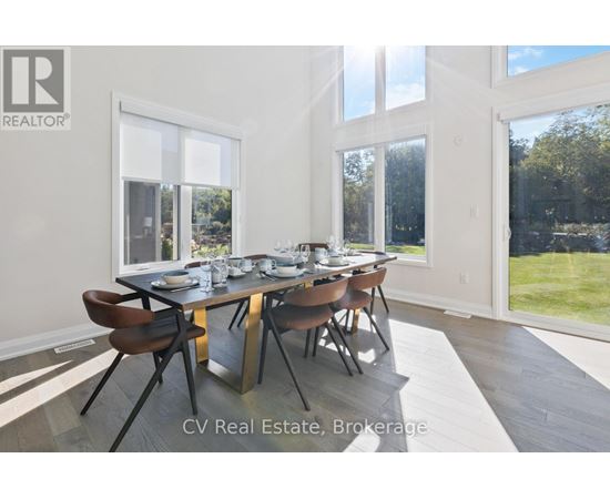 A dining room with a table set for six and a view of a lawn outside the window.