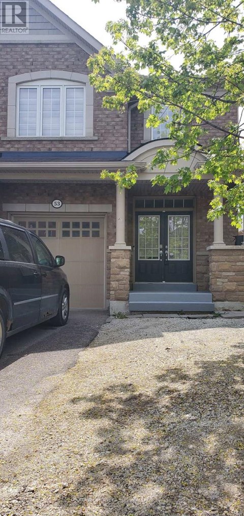A black car is parked in front of a house with a brown garage door.
