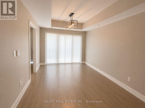 A spacious room with wooden flooring and a chandelier hanging from the ceiling.