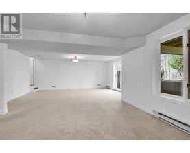 A spacious room with white walls and carpeted floor.