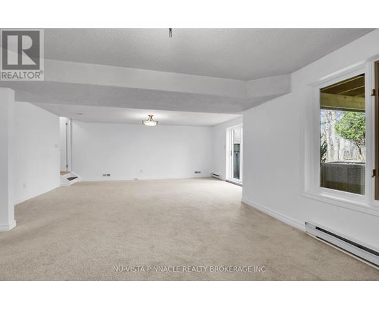 A spacious room with white walls and carpeted floor.