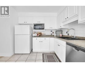 A kitchen with white cabinets and a fridge.